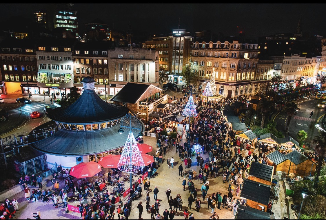 Aerial view of Bournemouth Square at night, crowded around the illuminated Christmas trees